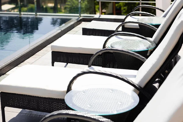 Chaises longues près de la piscine en station pendant la journée — Photo de stock