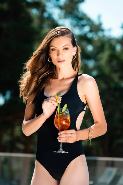 Attractive sexy woman in swimming suit posing with cocktail on resort — Stock Photo