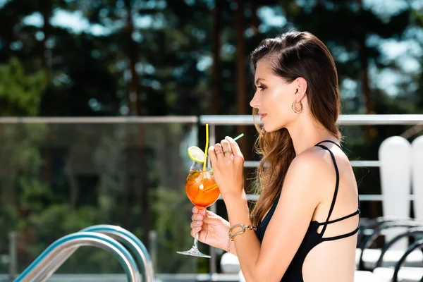 Vista lateral de mujer atractiva en traje de baño con cóctel en el resort - foto de stock