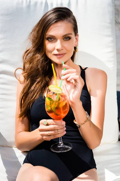 Attractive woman in swimming suit on sunbed with cocktail on resort — Stock Photo
