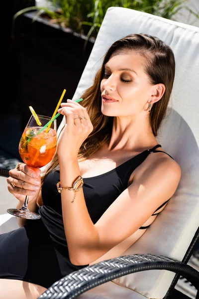 Séduisante femme en maillot de bain avec cocktail sur chaise longue en station balnéaire — Photo de stock