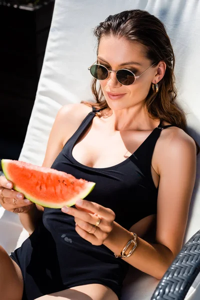 Beautiful woman in swimming suit with watermelon on sun bed — Stock Photo