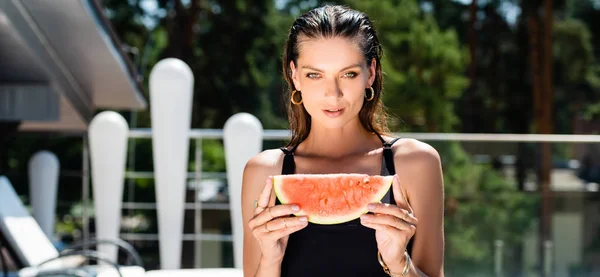 Panoramaaufnahme einer schönen Frau im Badeanzug, die mit Wassermelone im Resort posiert — Stockfoto