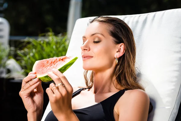 Beautiful woman in swimming suit with watermelon on sun bed — Stock Photo