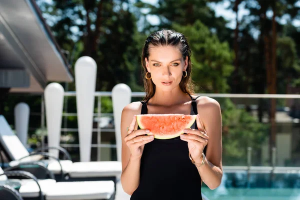 Beautiful woman in swimming suit posing with watermelon on resort — Stock Photo