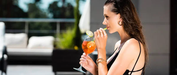 Plan panoramique de belle jeune femme en maillot de bain boire un cocktail au resort — Photo de stock
