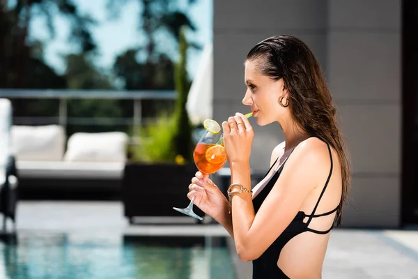 Красивая молодая женщина в купальнике, пьет коктейль на курорте — стоковое фото
