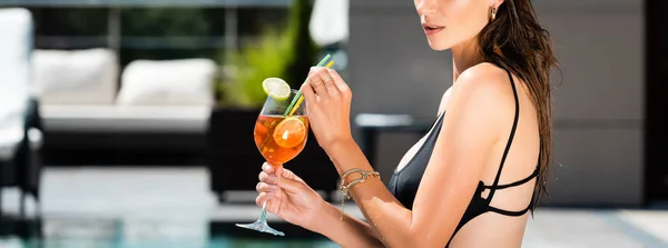 Panoramic shot of beautiful girl in swimming suit with cocktail on resort — Stock Photo