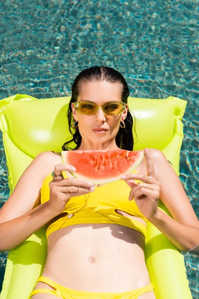 Beautiful girl on inflatable mattress with watermelon in pool on resort — Stock Photo