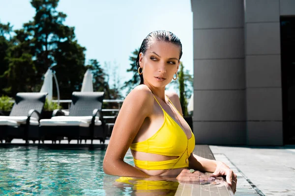 Bella donna sexy in costume da bagno in posa in piscina sul resort durante il giorno — Foto stock