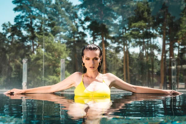 Schöne sexy Frau im Badeanzug schaut in Kamera im Pool auf Resort — Stockfoto