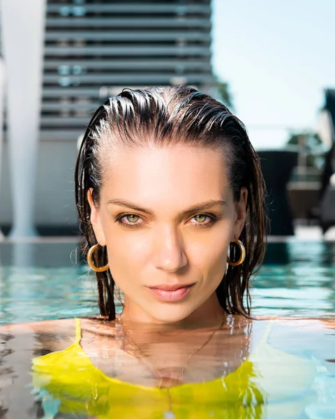 Beautiful woman looking at camera while posing in pool — Stock Photo