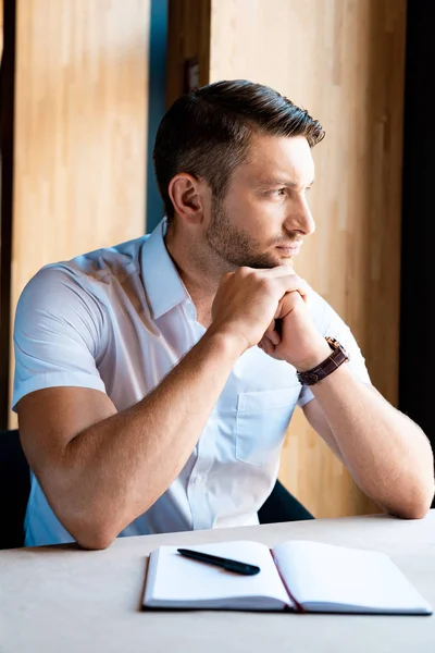 Pensive muscular man sitting with clenched hands in cafe — Stock Photo