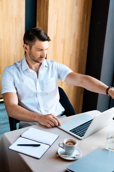Focused freelancer looking at laptop screen while sitting in cafe — Stock Photo