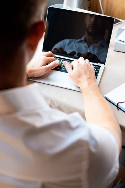 Vista recortada del hombre escribiendo en el teclado del ordenador portátil en la cafetería - foto de stock