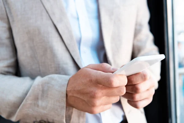 Обрезанный вид бизнесмена в формальной одежде, держащего смартфон — стоковое фото