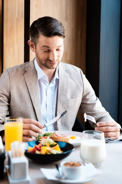 Smiling businessman in formal wear eating food in cafe — Stock Photo