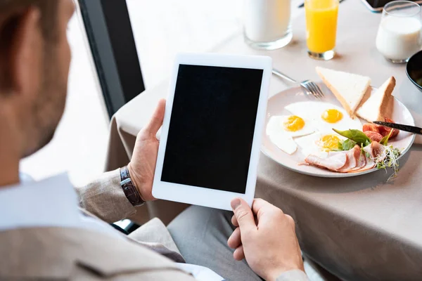 Vista recortada de hombre de negocios sosteniendo tableta digital con pantalla en blanco en la cafetería - foto de stock