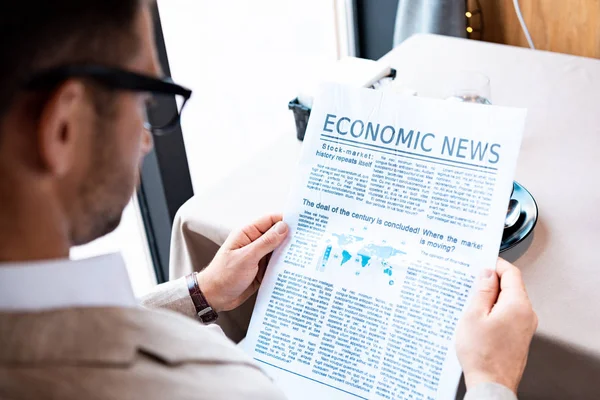 Cropped view of businessman reading newspaper in cafe — Stock Photo