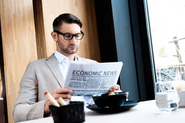 Focused businessman in glasses reading newspaper in cafe — Stock Photo