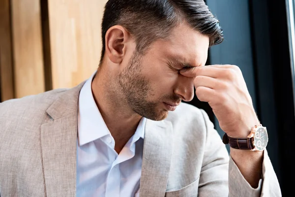 Tired businessman touching nose with closed eyes in cafe — Stock Photo