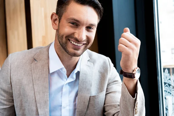 Homem de negócios sorridente em relógio de pulso olhando para a câmera no café — Fotografia de Stock