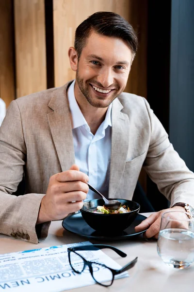 Smiling businessman looking at camera while eating in cafe — Stock Photo