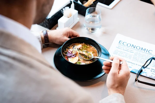 Vista cortada de empresário comendo à mesa com jornal no café — Fotografia de Stock