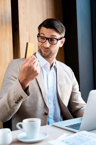 Uomo d'affari in occhiali con carta di credito e computer portatile in caffè — Foto stock