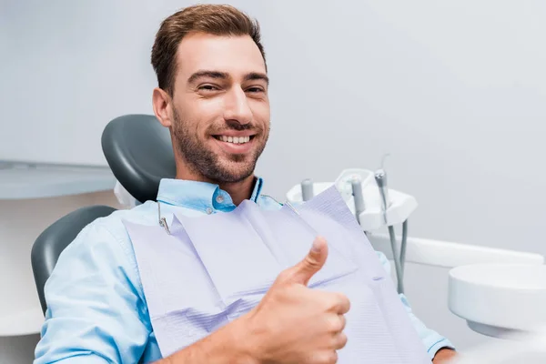 Счастливый бородатый мужчина улыбается и показывает большой палец вверх в стоматологической клинике — стоковое фото