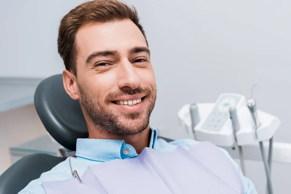 Homme barbu joyeux souriant et regardant la caméra dans la clinique dentaire — Photo de stock