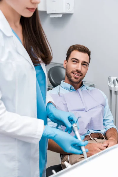 Enfoque selectivo del hombre alegre mirando al dentista en la clínica - foto de stock