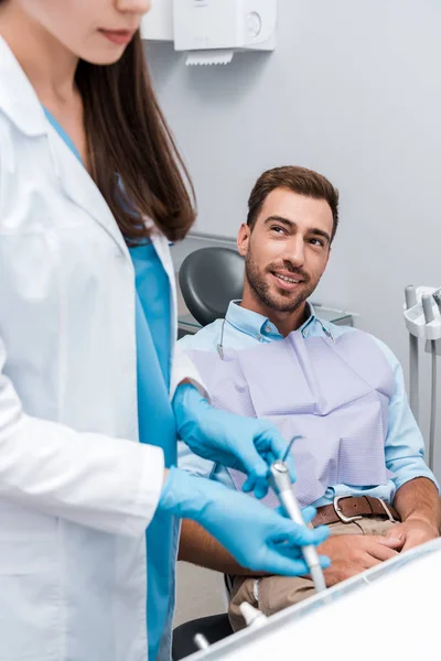 Messa a fuoco selettiva di uomo allegro guardando dentista in clinica — Foto stock