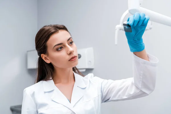 Вибірковий фокус привабливого стоматолога, який дивиться на рентген в клініці — стокове фото