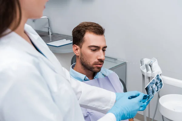 Selective focus of man looking at x-ray near dentist in white coat — Stock Photo