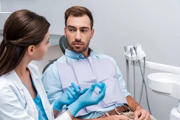 Selective focus of patient looking at dentist with retainer in hands — Stock Photo