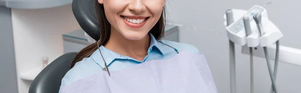 Панорамный снимок веселой женщины, улыбающейся в стоматологической клинике — стоковое фото