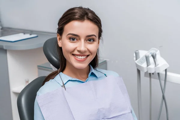 Hermosa mujer sentada y sonriendo en la clínica dental - foto de stock