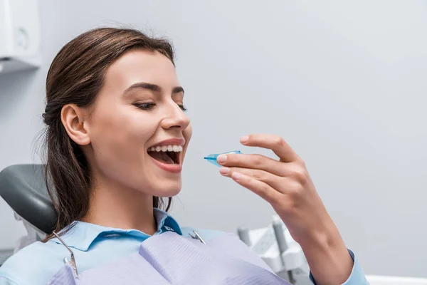 Cheerful woman with opened mouth holding retainer in dental clinic — Stock Photo