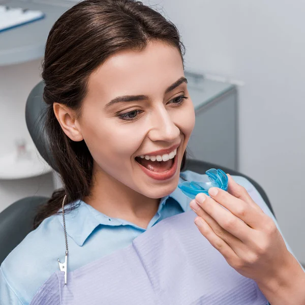 Счастливая женщина с синим гонораром в стоматологической клинике — стоковое фото