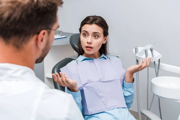 Вибірковий фокус привабливої жінки, що показує жест згинання біля стоматолога в клініці — стокове фото