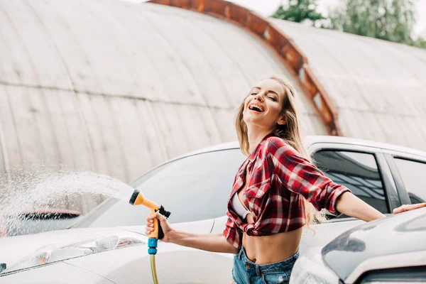 Selective focus of cheerful girl holding pressure washer near card — Stock Photo