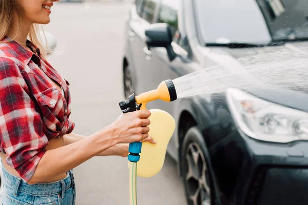 Cropped view of cheerful girl washing black car — Stock Photo