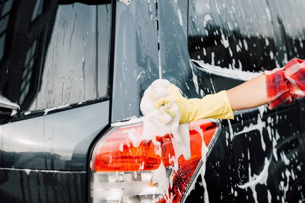 Vista cortada de menina em luva de látex perto de carro molhado em espuma — Fotografia de Stock