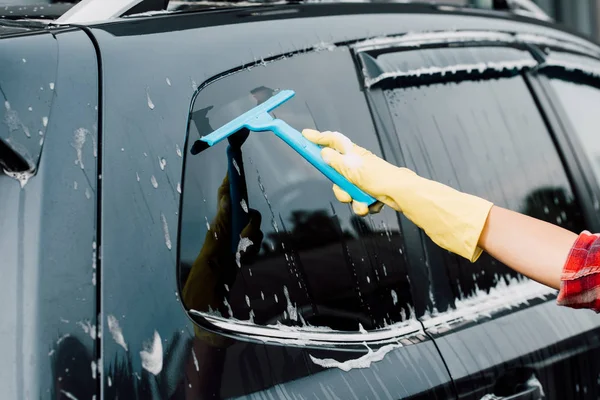 Vista cortada de mulher lavando carro preto com rodo — Fotografia de Stock