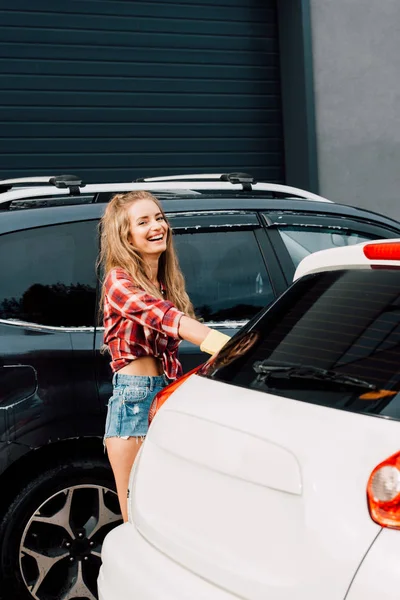 Mulher feliz de pé e sorrindo perto de automóveis modernos — Fotografia de Stock