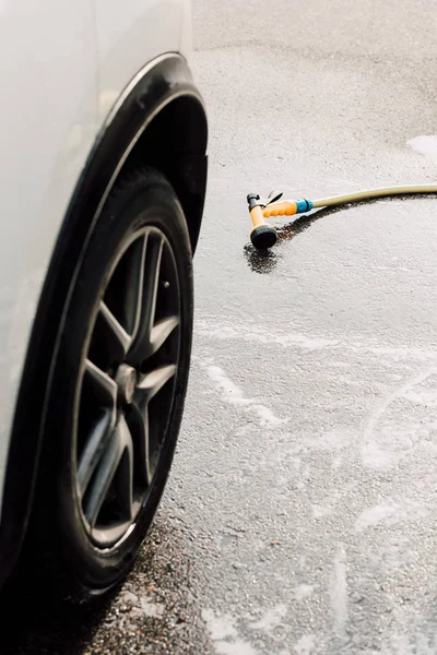 White luxury and modern car near pressure washer on asphalt — Stock Photo