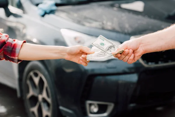 Мужчина давал деньги женщине рядом с машиной — стоковое фото