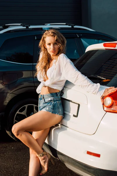 Молодая красивая женщина в сексуальных джинсовых шортах возле машин — стоковое фото