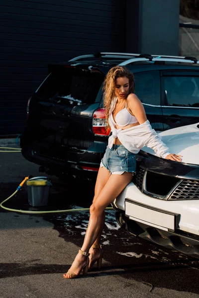 Приваблива молода жінка стоїть біля мокрих автомобілів класу люкс — стокове фото